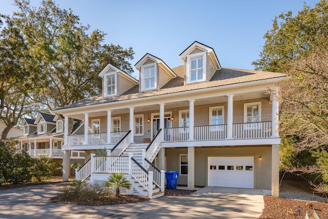 beach home featuring stucco siding, a porch, concrete driveway, stairway, and a garage