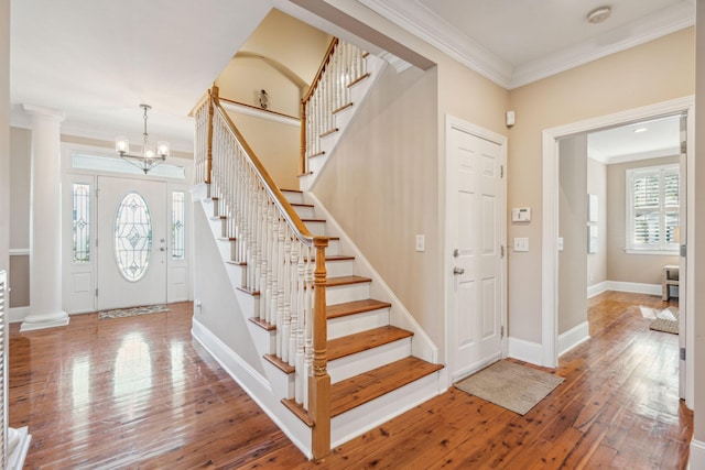 entryway featuring a wealth of natural light, ornate columns, crown molding, and hardwood / wood-style floors