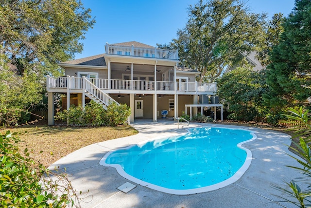 rear view of house featuring a ceiling fan, a patio area, a balcony, an outdoor pool, and stairs