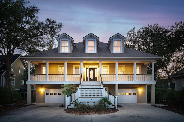 coastal home with concrete driveway, a porch, stairway, and an attached garage