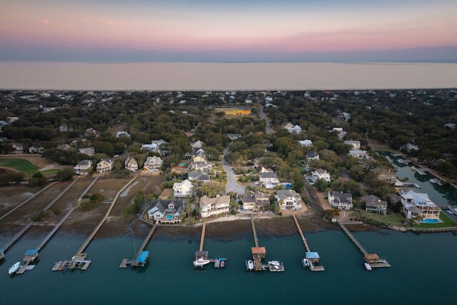 aerial view at dusk featuring a water view and a residential view