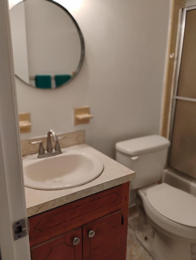 bathroom featuring tile patterned flooring, vanity, toilet, and a shower with shower door