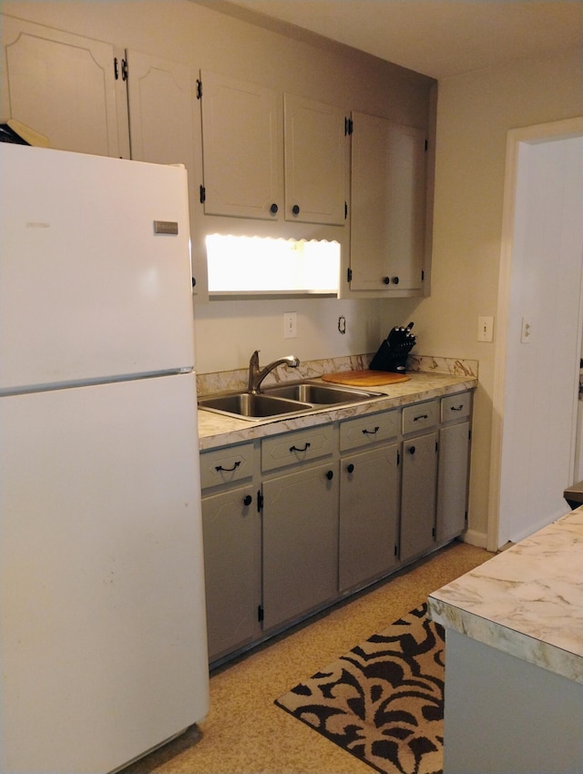 kitchen featuring white refrigerator, gray cabinetry, and sink