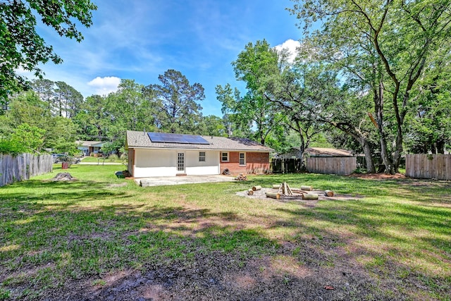 403 Forest Cir, Summerville, SC 29483 - back of house featuring a patio, a fenced backyard, roof mounted solar panels, a lawn, and an outdoor fire pit
