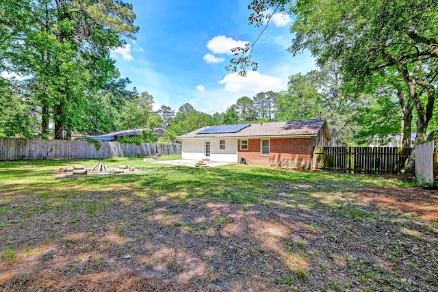 403 Forest Cir, Summerville, SC 29483 - back of property featuring a fire pit, a patio, a fenced backyard, a lawn, and solar panels