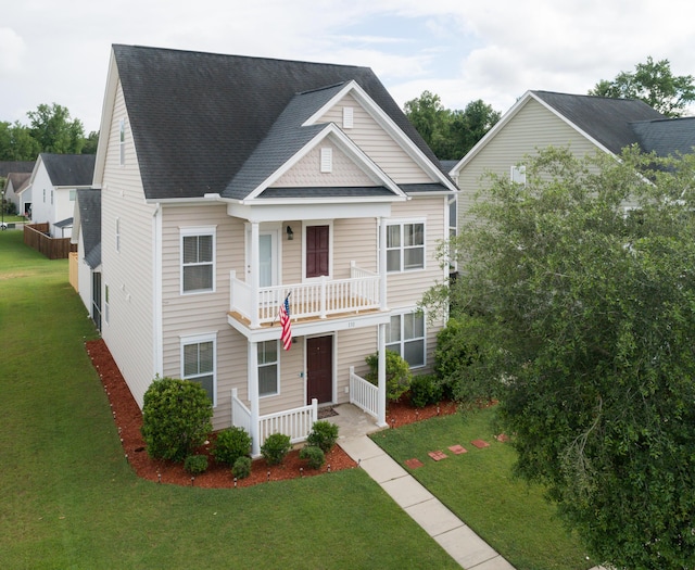 view of front of property featuring a balcony, covered porch, and a front lawn