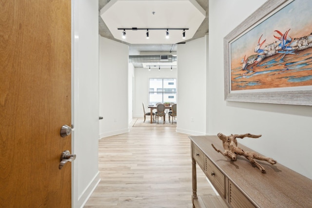 hallway with light wood-type flooring and track lighting