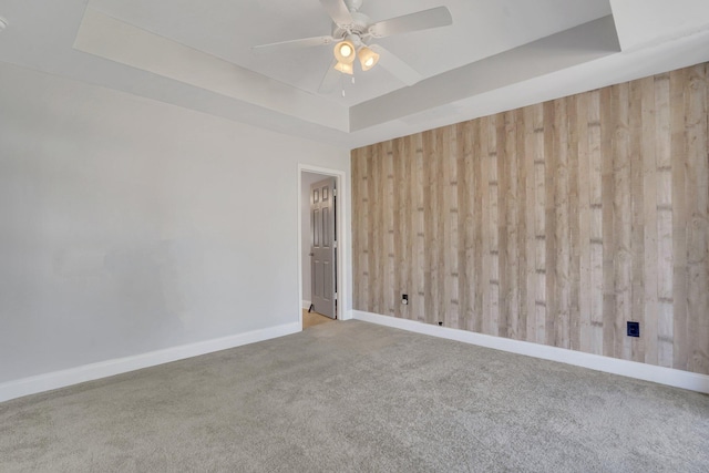 spare room with wood walls, carpet, and a tray ceiling