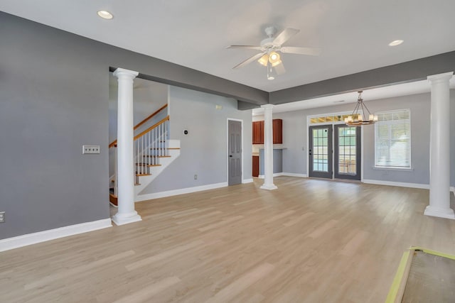 unfurnished living room with ornate columns, french doors, ceiling fan with notable chandelier, and light wood-type flooring