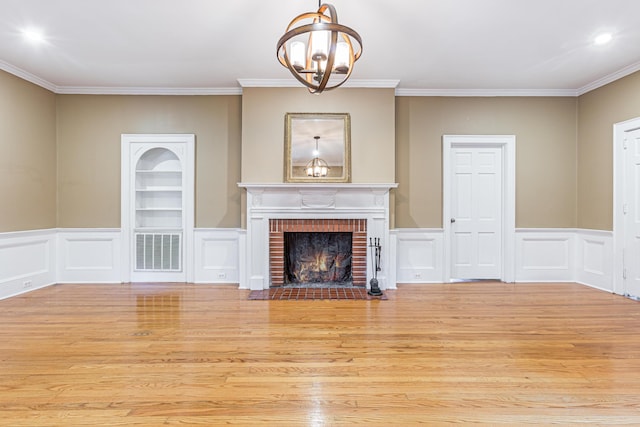 unfurnished living room with crown molding, an inviting chandelier, a fireplace, and light hardwood / wood-style floors