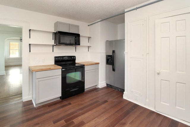 kitchen featuring dark hardwood / wood-style flooring, wooden counters, black appliances, and a textured ceiling