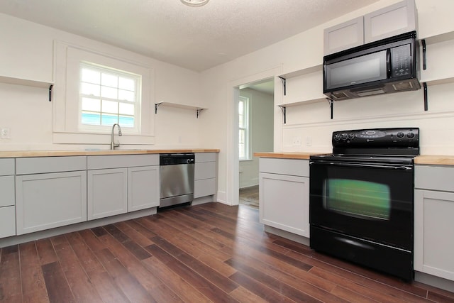 kitchen featuring dark wood-type flooring, black appliances, white cabinets, sink, and butcher block counters