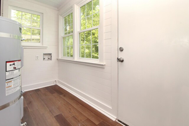 doorway to outside featuring dark hardwood / wood-style flooring, strapped water heater, and wooden walls