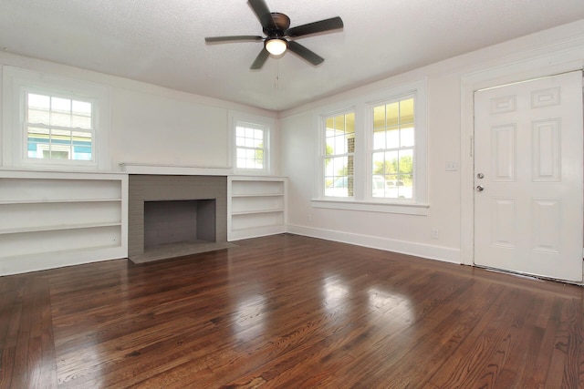 unfurnished living room featuring a fireplace, dark hardwood / wood-style flooring, a wealth of natural light, and ceiling fan