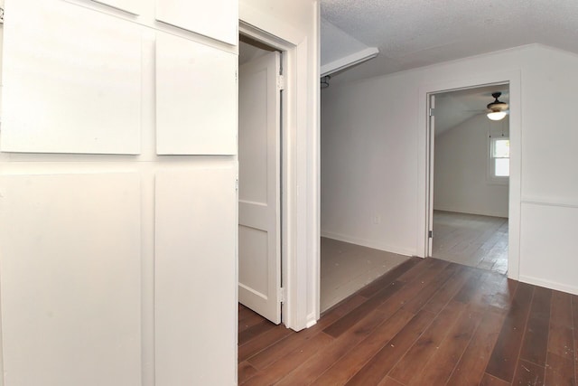 corridor featuring a textured ceiling, lofted ceiling, and dark wood-type flooring