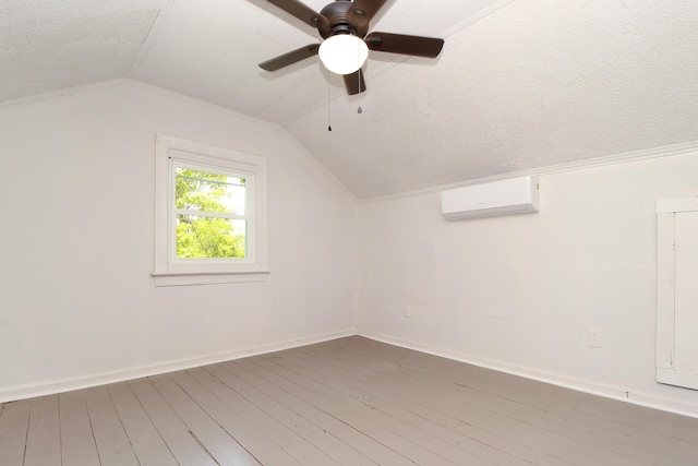 bonus room featuring hardwood / wood-style flooring, lofted ceiling, a textured ceiling, and a wall unit AC