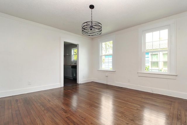 unfurnished room featuring dark hardwood / wood-style flooring, a textured ceiling, plenty of natural light, and a notable chandelier