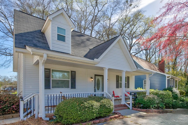 view of front of home with roof with shingles and a porch