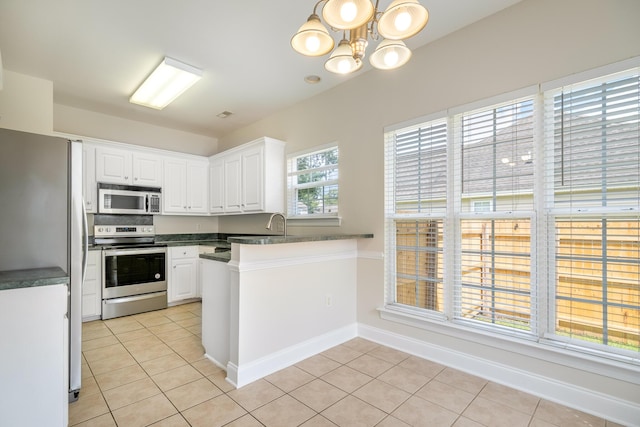 7812 Spring Creek Rd, North Charleston, SC 29418 - kitchen with appliances with stainless steel finishes, light tile patterned floors, a peninsula, white cabinetry, and dark countertops