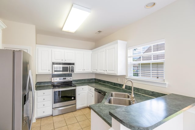 7812 Spring Creek Rd, North Charleston, SC 29418 - kitchen with stainless steel appliances, a peninsula, dark countertops, white cabinets, and light tile patterned flooring