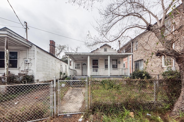 shotgun-style home featuring a porch, a fenced front yard, and a gate