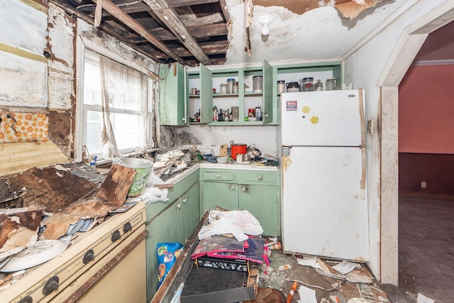 kitchen with open shelves, light countertops, green cabinetry, and freestanding refrigerator