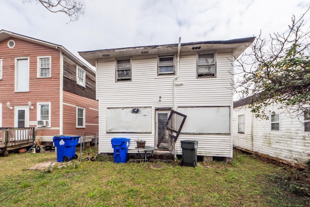 rear view of house featuring cooling unit and a lawn