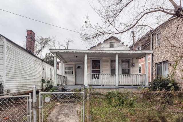 shotgun-style home featuring a fenced front yard, a gate, and a porch