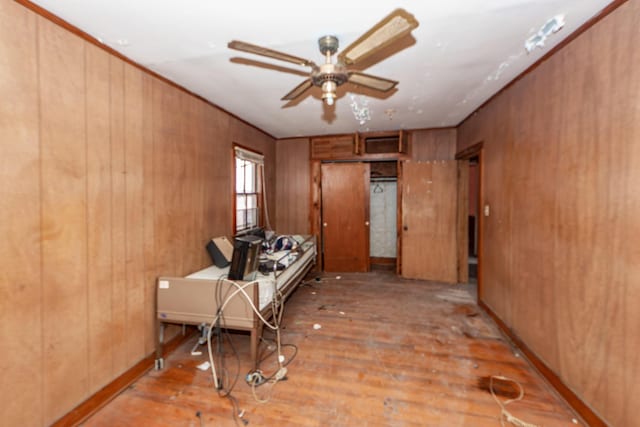 interior space with light wood-style floors, a ceiling fan, and wood walls