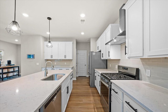 217 Lucca Dr, Summerville, SC 29486 - kitchen with light stone counters, stainless steel appliances, white cabinets, hanging light fixtures, and wall chimney range hood