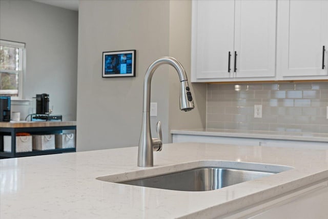 217 Lucca Dr, Summerville, SC 29486 - interior details with light stone counters, white cabinetry, a sink, and backsplash