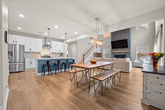 217 Lucca Dr, Summerville, SC 29486 - dining space with light wood-type flooring, a warm lit fireplace, stairs, and recessed lighting