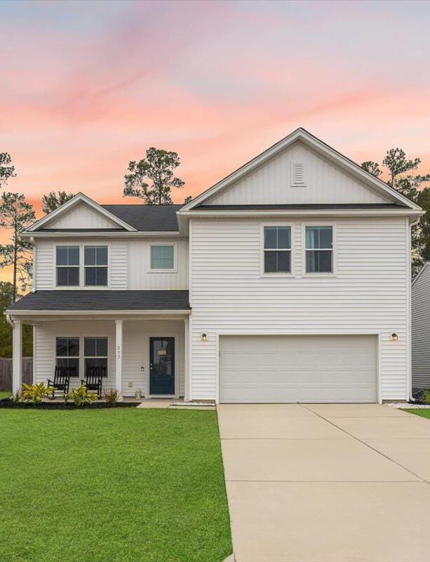 217 Lucca Dr, Summerville, SC 29486 - traditional home with an attached garage, a porch, concrete driveway, and a yard