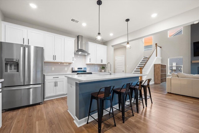 217 Lucca Dr, Summerville, SC 29486 - kitchen with stainless steel appliances, white cabinets, light countertops, and wall chimney exhaust hood