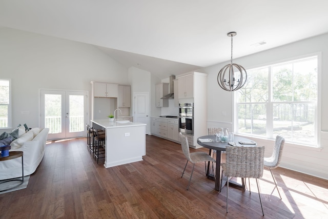 dining room featuring an inviting chandelier, a wealth of natural light, french doors, and dark hardwood / wood-style flooring