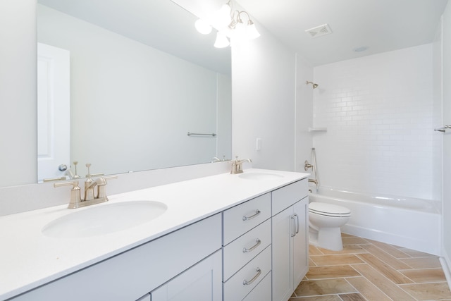 full bathroom featuring toilet, large vanity, double sink, tiled shower / bath combo, and an inviting chandelier