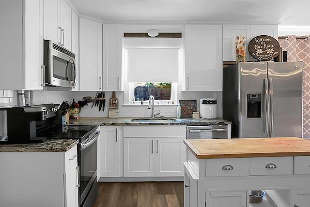 kitchen with a sink, wood counters, appliances with stainless steel finishes, and white cabinets