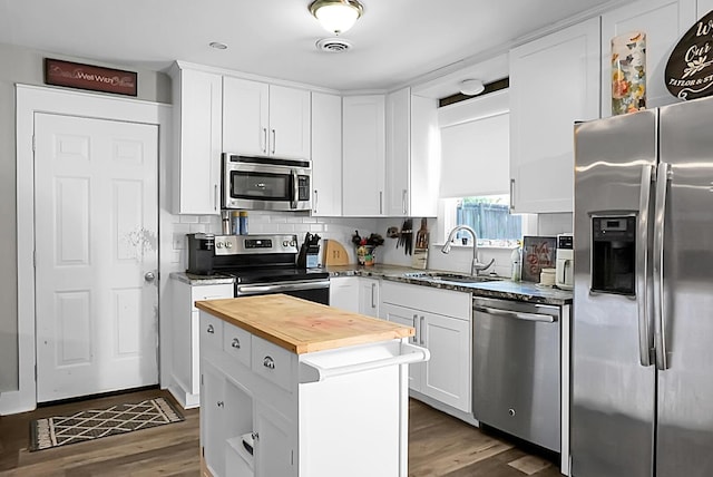 kitchen featuring visible vents, wooden counters, a sink, appliances with stainless steel finishes, and white cabinetry