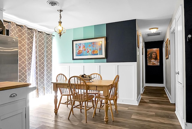 dining room featuring visible vents, dark wood-style flooring, and a decorative wall