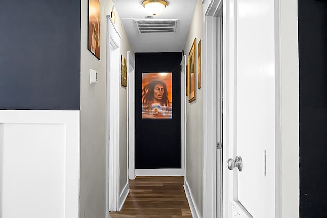 hallway featuring visible vents, baseboards, and dark wood finished floors