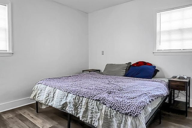 bedroom featuring multiple windows, baseboards, and wood finished floors