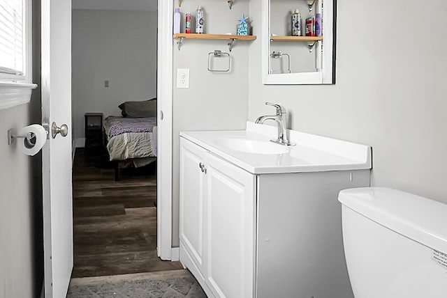 half bathroom with toilet, vanity, and wood finished floors