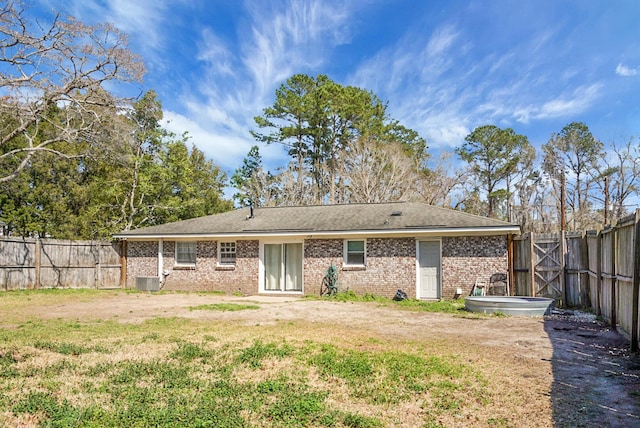 back of property featuring a yard, brick siding, and a fenced backyard