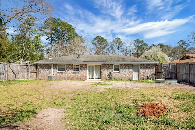 back of property featuring brick siding, a lawn, and a fenced backyard