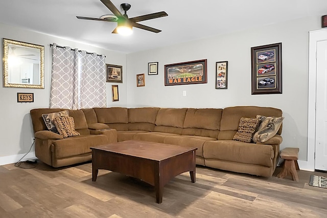 living room featuring baseboards, ceiling fan, and wood finished floors