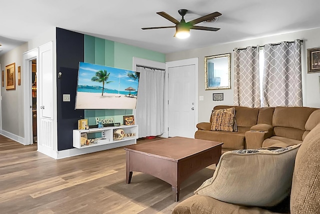 living room featuring baseboards, wood finished floors, and a ceiling fan