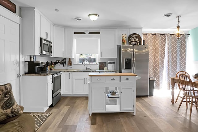 kitchen featuring visible vents, stainless steel appliances, wood finished floors, and a sink