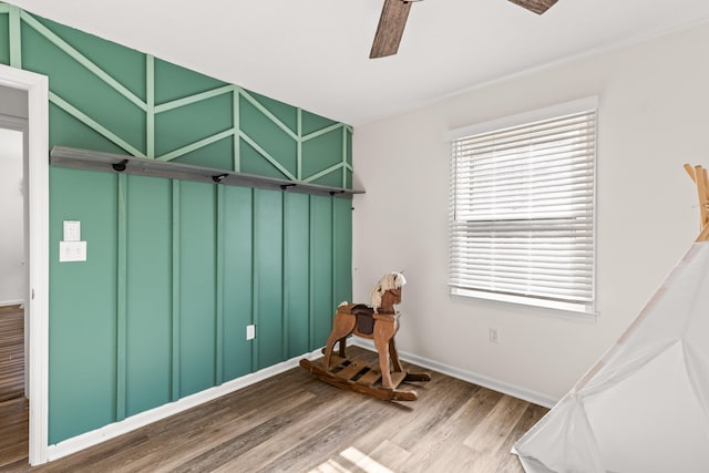 misc room with baseboards, wood finished floors, and a ceiling fan