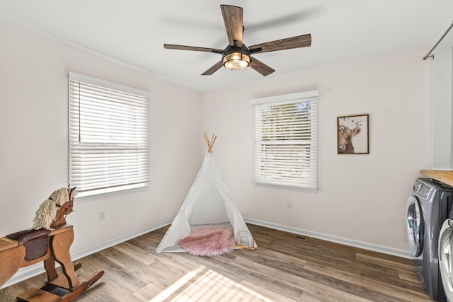 playroom featuring ceiling fan, wood finished floors, baseboards, and washing machine and clothes dryer