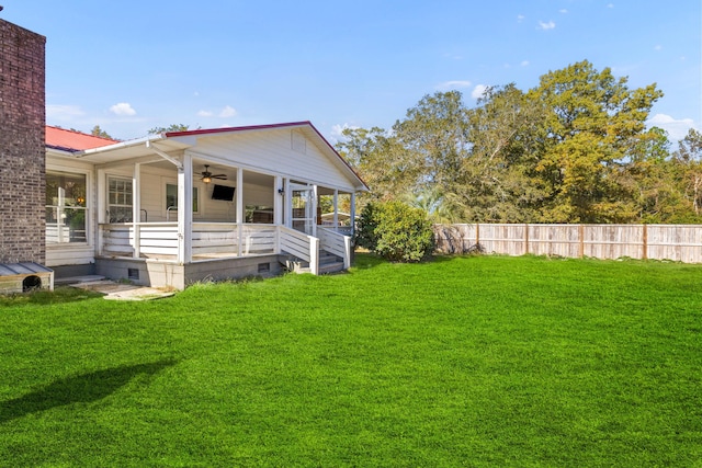 view of yard featuring fence, a ceiling fan, and a sunroom